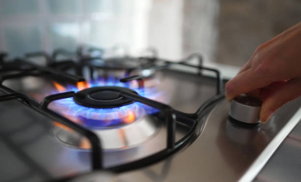 Woman turning on the gas burner on the stove. stock photo