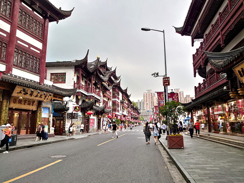 Shanghai, China - Jul 23, 2018: A traditional Chinese architectural-style street in Yuyuan Garden with no cars and pedestrians walking passing the shops without masks before the pandemic