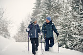 Middle aged couple hiking in beautiful forest it European Alps mountains on an overcast  winter day