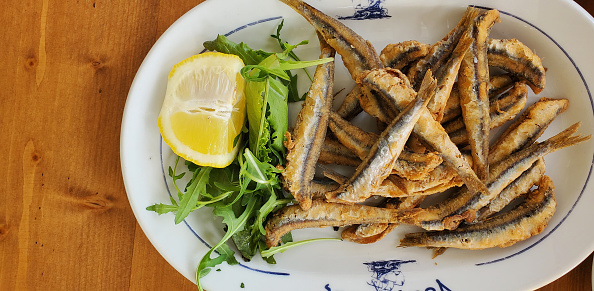 small fish deep-fried with lemon and herbs on a white plate. light and tasty snack for beer. seafood at the beach cafe