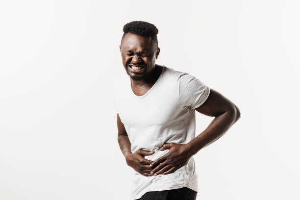 Stomach pain. Pancreatitis disease of pancreas becomes inflamed. Sick african american man hold abdomen because it hurts. Stomach pain. Pancreatitis disease of pancreas becomes inflamed. Sick african american man hold abdomen because it hurts endometriosis bloated stock pictures, royalty-free photos & images