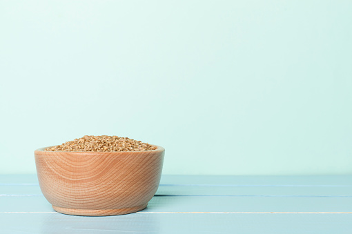 Bowls with wholegrain spelt farro on wooden table.