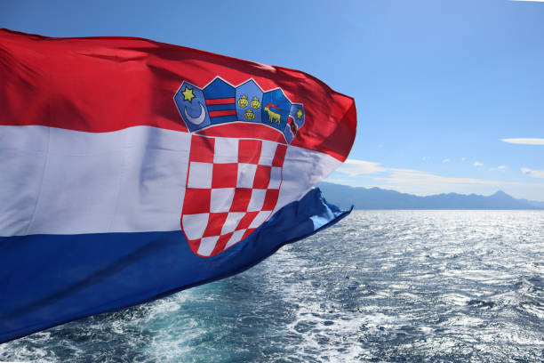 la bandera de croacia ondea en el viento contra el fondo del mar y el cielo, de cerca - croatian flag fotografías e imágenes de stock