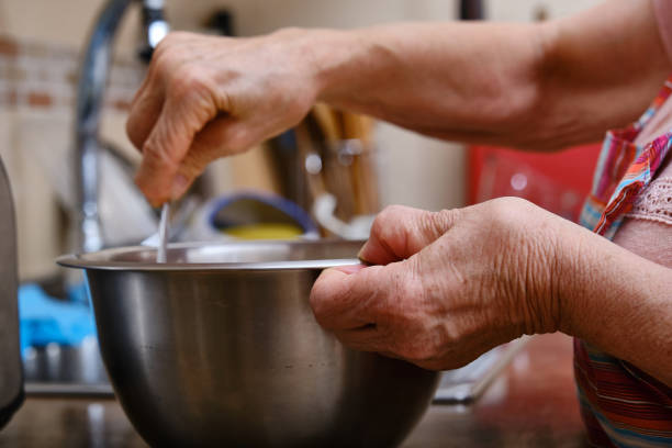 Detail of the hands of an elderly woman with arthritis cooking stock photo