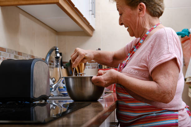 Older woman with arthritis in her hands cooking. stock photo