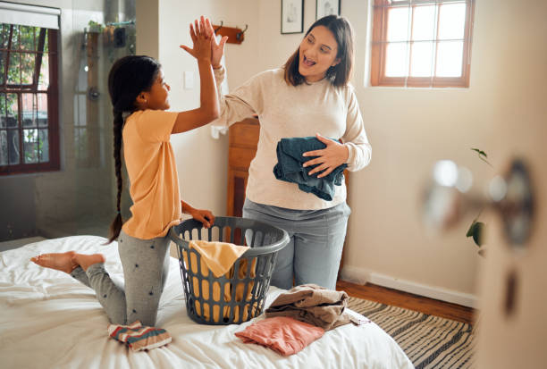istock Cleaning, high five and child and mother doing laundry clothes, house work and fold clean fabric. Love bond, home bedroom or happy family kid with basket container and celebrate domestic housekeeping 1474691412