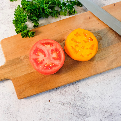 Red And Orange Tomato Slices On A Cutting Board