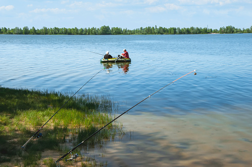 Men on an inflatable boat in the river fishing with fishing rods