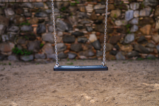 Empty childrens wooden swing in a walled playground