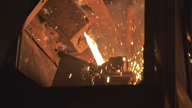 Molten metal melting, operator work hard tapping molten metal from furnace to ladle for pouring to in foundry factory