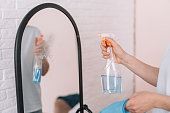 Lady with a rag in her hands sprays detergent on the mirror