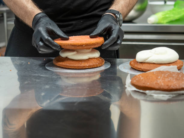 istock pastry chef preparing a three floor frosted cake , assembling spongy red velvet layers with buttercream 1474708594