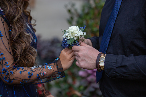 A young man gives his date a corsage.