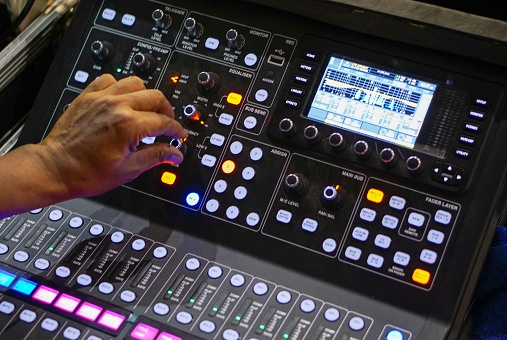 Hand adjusting audio mixer. Male producer, sound engineer hands working on audio mixing console in broadcasting, recording studio.