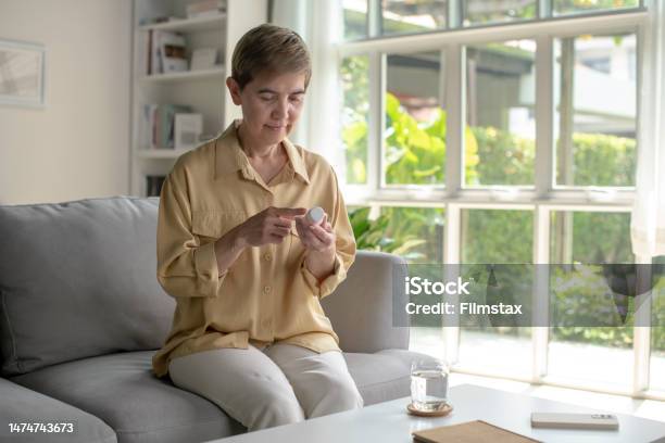 Mature Woman Read Medicine Instruction On Packaging Stock Photo - Download Image Now
