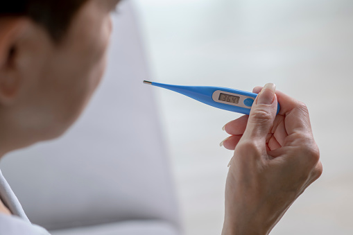 Woman holding digital thermometer.
