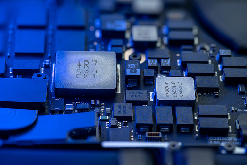 Close-up of a computer circuit board, microchips and other elements with soft blue neon lighting