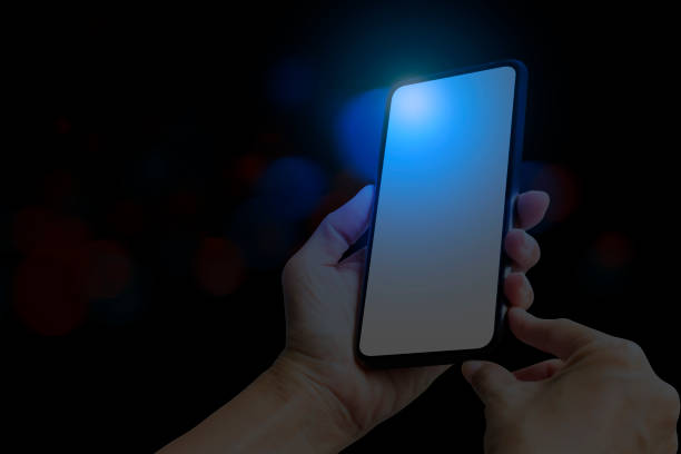 istock Hand-holding smart phone at night. Bokeh purple background 1474750110