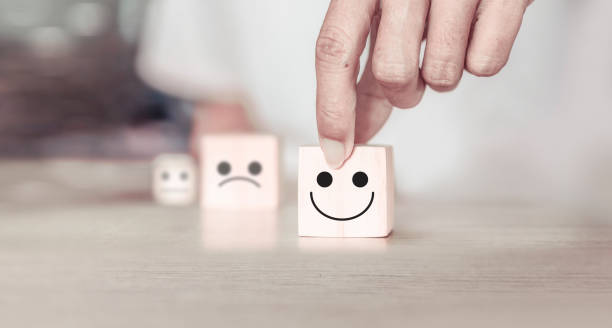 istock Hand choose smile face and blurred sad face icon on wood cube block. Customer services best excellent business rating experience. Satisfaction survey concept. 1474750130