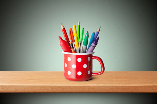 Pen holder with colored pens and pencils on the shelf.