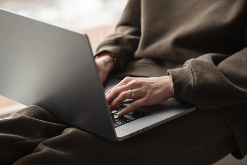 Close-up shot of female hands using laptop at the window