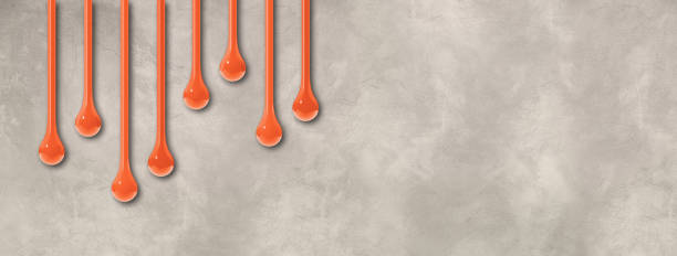 istock Orange ink drops on light concrete wall. Horizontal banner 1474759230