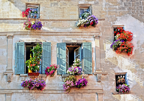 Typical facade of the old Provencal retro house with windows and wooden shutters decorated with colorful fresh flowers in Provence, Cote d'Azur, France