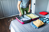 Adult man packing clothes in suitcase for vacation