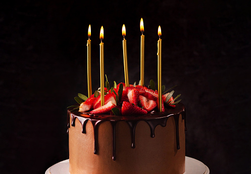 Birthday chocolate cake with candles. Candles on top of a birthday cake with strawberry black background