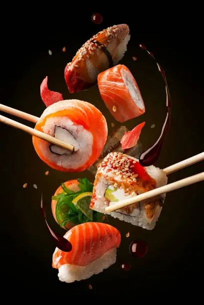 Photo of Sushi Rolls in assortment on the air. Concept of levitation. black background.