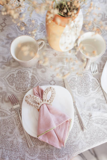 istock Spring festive dining table setting with flowers, napkins and cute bunny decor on linen tablecloth. Easter time. Cozy home 1474770785