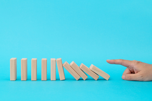 Woman hand pushing domino pieces.