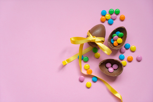 Easter chocolate eggs and sugar multicolored on pink background
