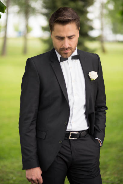Groom waiting for his bride. Hand in pocket, looking down, not sure of his role in the wedding event.