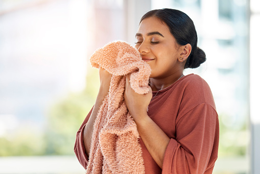 Mujer que huele a ropa limpia, manta o tela para un olor fresco y limpio en la casa después de lavar, limpiar y hacer la limpieza. Limpiador femenino feliz con textil para aroma, fragancia y aroma photo
