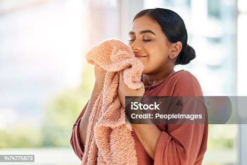istock Woman smelling clean laundry, blanket or fabric for fresh and clean smell in house after doing washing, cleaning and housekeeping. Happy female cleaner with textile for aroma, fragrance and scent 1474775873
