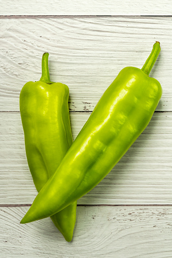 Green peppers on a white wooden table background
