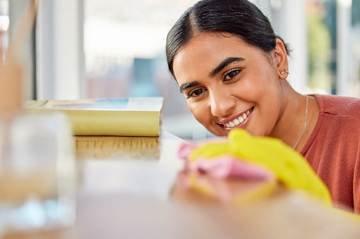 Cleaning, surface and woman with cloth for dirt, dust and bacteria on furniture at home. Happy cleaner, housekeeping and maid wipe table, shelf and living room for routine maintenance, safety or care