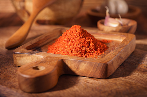 Red ground paprika in a wooden bowl on a rustic background