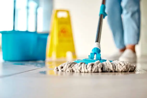 Mop, cleaner and washing wet floor for hygiene, disinfection or sanitary area for cleanliness at the workplace. Housekeeper cleaning dirty flooring for sanitization, water or wash indoors
