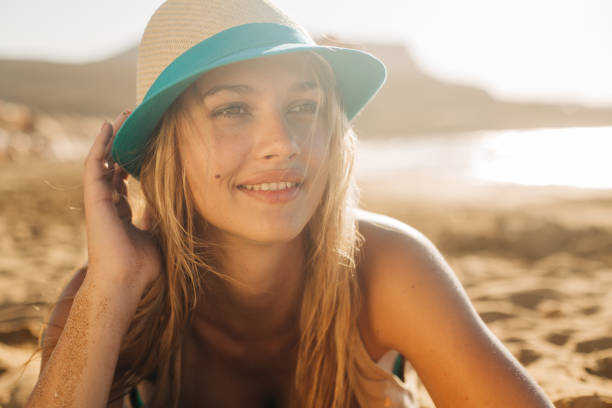 istock Young woman with summer hat lying on the sand 1474782962