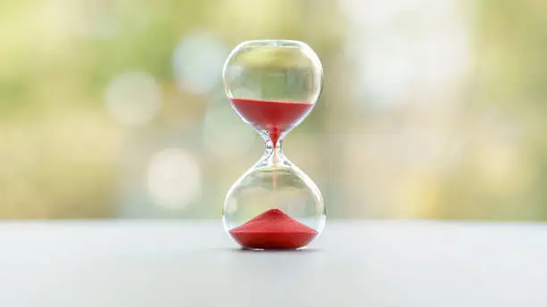 Red hourglass with blurred nature background