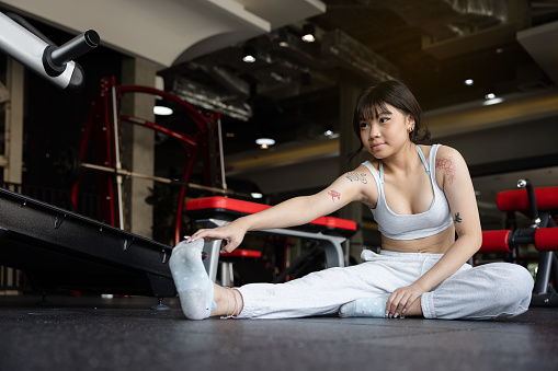 Asian teenage girl stretching working out in the gym