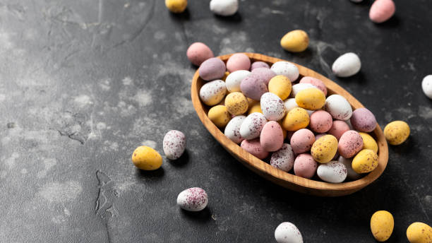 Easter mini eggs, chocolate candy in wooden bowl
