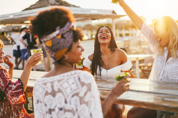 Happy girls having fun drinking cocktails at bar on the beach - Focus on african girl face stock photo