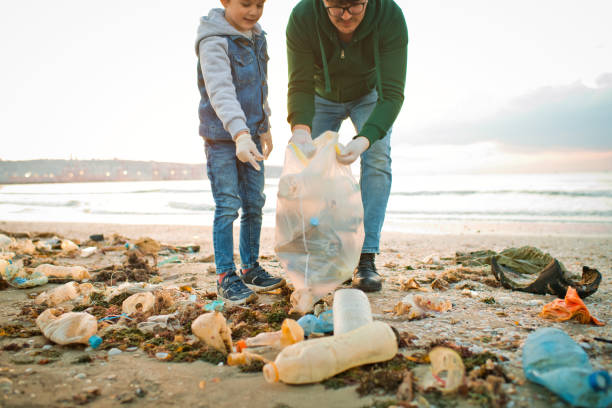 istock Family volunteers cleans a beach by gathering discarded plastic waste. Environmental pollution and ecological problems concept. 1474788559