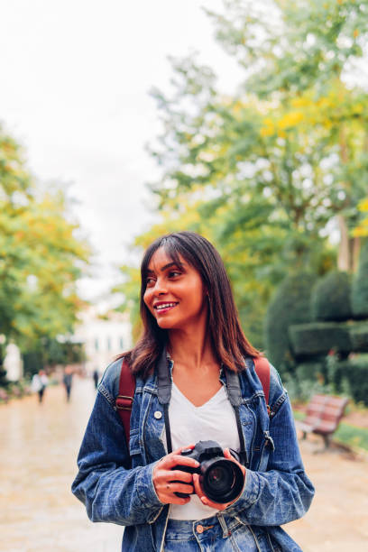 istock Smiling woman with camera in park 1474789202