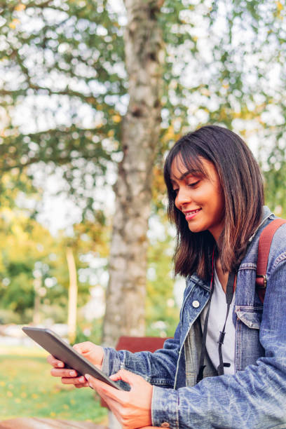 istock Latin student girl, using digital tablet outdoors. Technology and online activity concept. 1474789221