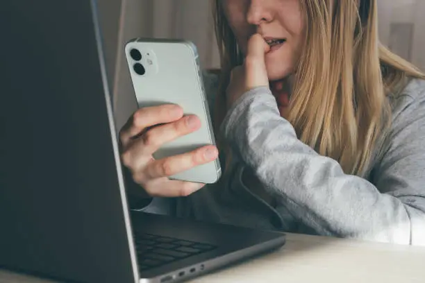 Cropped portrait of female blogger biting fingers nervous using mobile phone. Panic, shock, bullying concept. High quality toned photo about technology and security