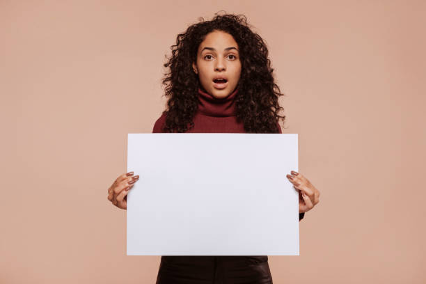 istock Young surprised multiracial woman holding blank banner 1474789641